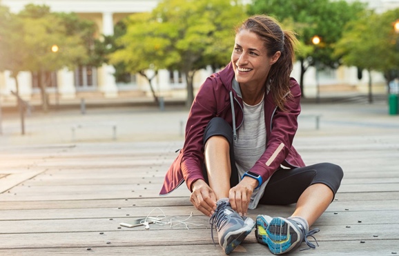 Sitting woman smiling and tying her shoes